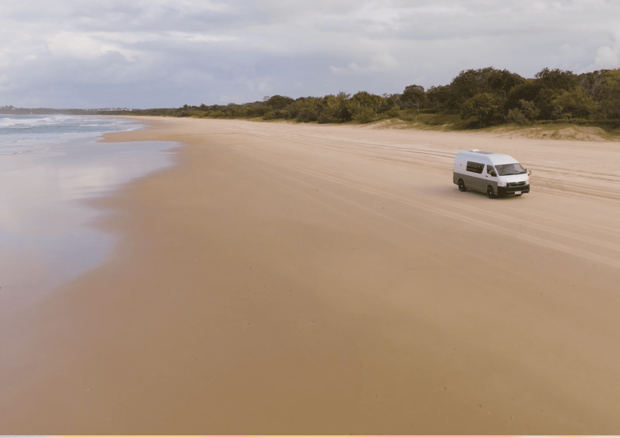 A Hiace campervan parked on the beach — the Bare Camper dream